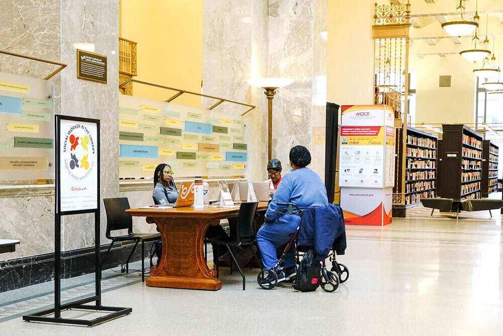 social worker in a library consulting with a customer in a wheelchair