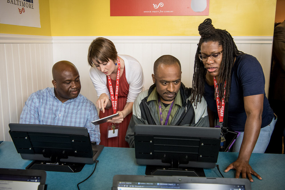 staff helping people with laptop computers